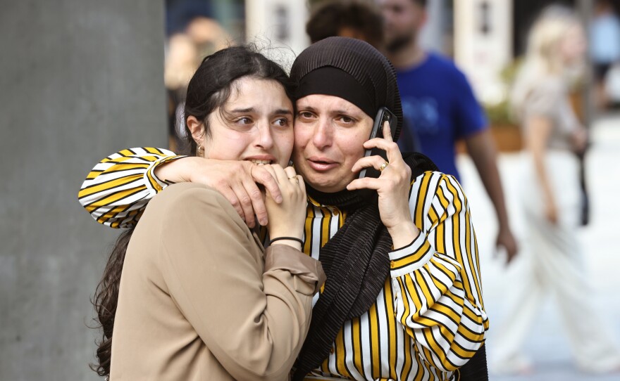 People evacuated from the Fields shopping center react, in Orestad, Copenhagen, Denmark, on Sunday after reports of shots fired.