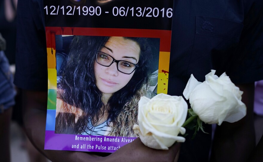 A man holds a portrait of Amanda Alvear at a vigil for the victims of the Pulse nightclub shooting, on Monday evening at the Dr. Phillips Center for the Performing Arts in Orlando, Fla.