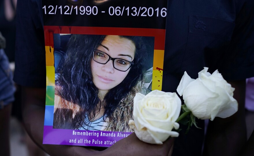 A man holds a portrait of Amanda Alvear at a vigil for the victims of the Pulse nightclub shooting, on Monday evening at the Dr. Phillips Center for the Performing Arts in Orlando, Fla.