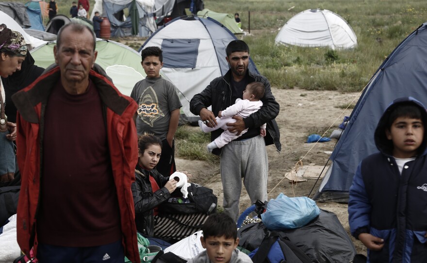 Refugees and migrants wait to be transferred by buses Tuesday during the evacuation of the camp near the Greek village of Idomeni. At its height, there were more than 12,000 people crammed into the makeshift camp, which exploded in size when Balkan states began closing their borders in mid-February.
