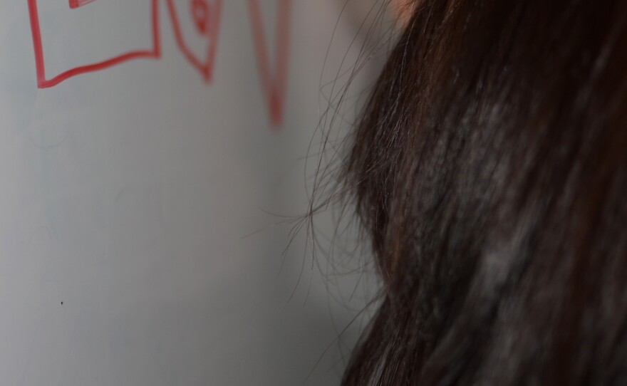 With lessons over, a teenage girl living at La Casa del Jardin draws on the whiteboard. The curriculum includes English lessons, as well as music, art, and yoga.