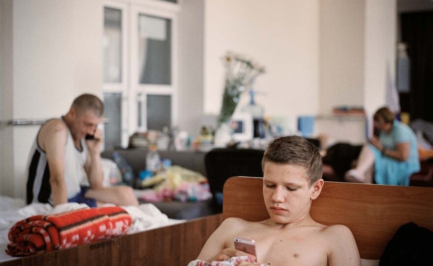 A boy lying in bed at a shelter that provides more permanent accommodation for internally displaced people at a factory owned by the Ukrainian Association for the Blind in Dnipro city, June 2022.
