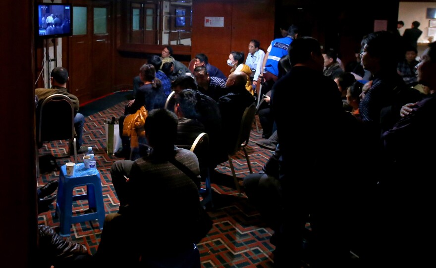 Loved ones of the passengers who were onboard the missing flight watch a televised press conference on Saturday in Beijing.