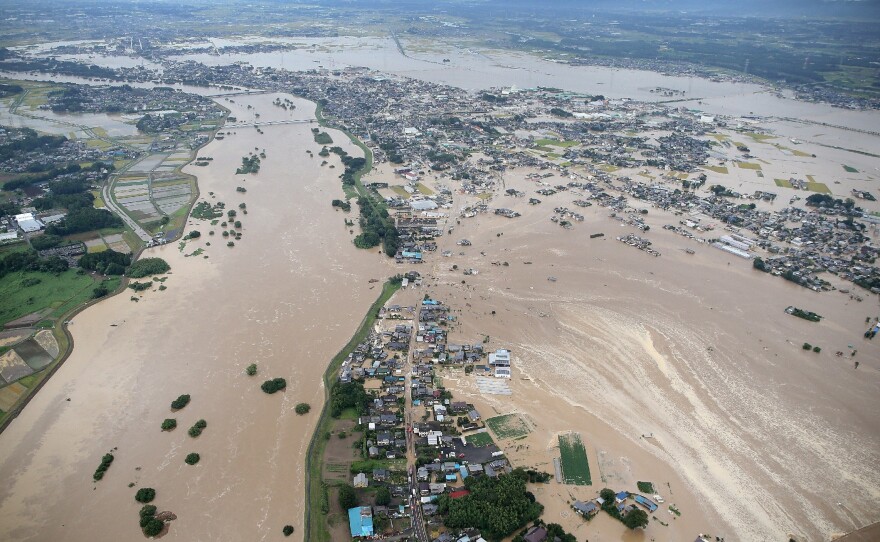 Floodwaters from the burst Kinugawa river, left, flow into a residential area, right, in Joso, Ibaraki Prefecture, Thursday. The city is northeast of Tokyo.