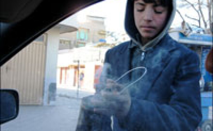 Fahim, 11, waves his can of burning incense inside a car on a busy Kabul street, seeking alms from the driver.