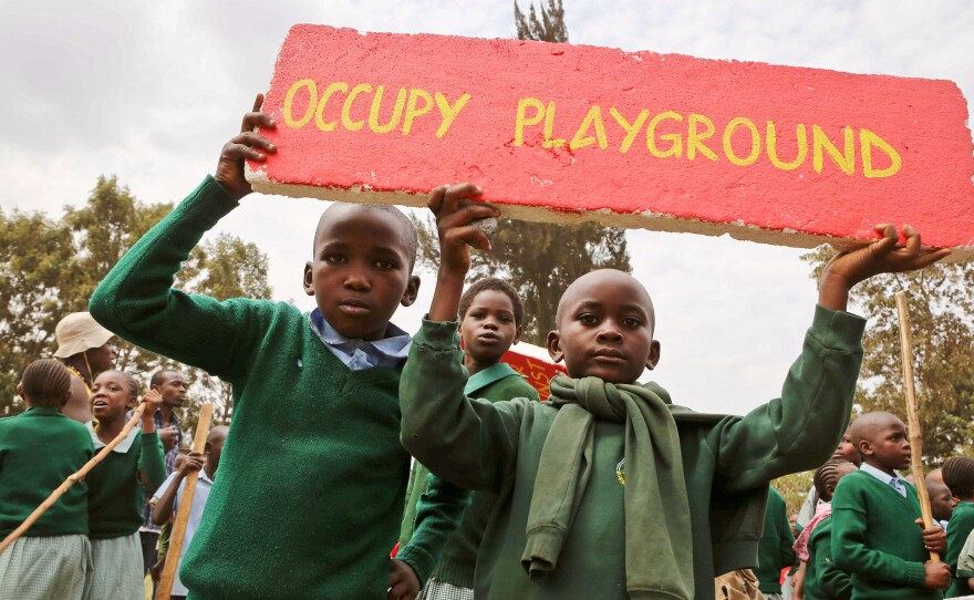 School kids hold up a sign given to them by activists at a demonstration at Langata Primary Road School.