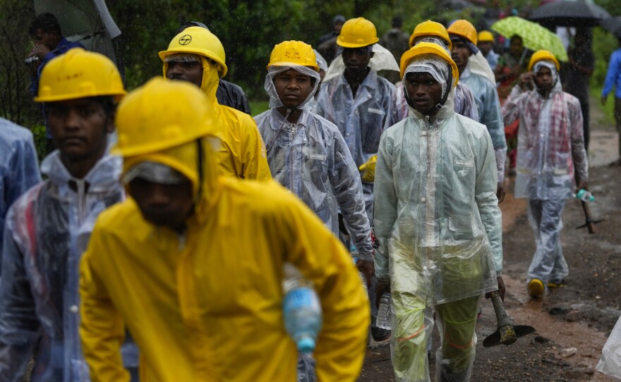 Rescuers walk towards the site of a landslide in Raigad district, western Maharashtra state, India, Thursday, July 20, 2023. While some people are reported dead many others feared trapped under piles of debris.