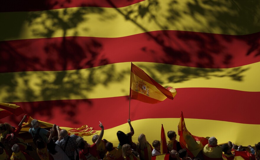 A nationalist activist waves a Spanish flag in front of a giant Catalan flag during a mass rally against Catalonia's declaration of independence, in Barcelona on Sunday.
