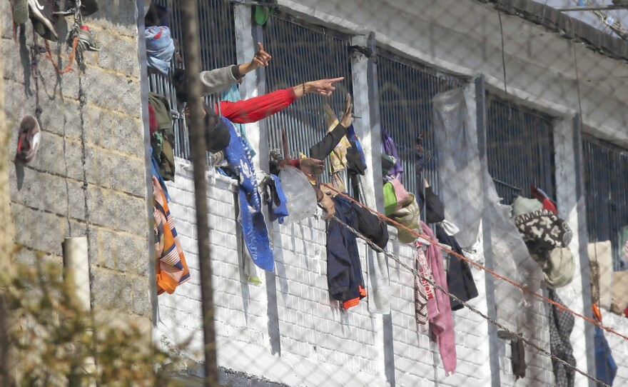 Inmates point from inside the La Modelo facility in Bogotá, Colombia, on Sunday. Violence broke out in the prison out of inmates' fears that prison guards are not doing enough to prevent coronavirus inside overcrowded prisons.