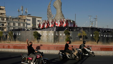A man reacts to the camera while driving past a monument depicting the clenched fist of the late Iranian Supreme Leader Ayatollah Ali Khamenei, who was killed in U.S. and Israeli strikes on Feb. 28, and a missile at the Islamic Revolution square in downtown Tehran, Iran, Tuesday.
