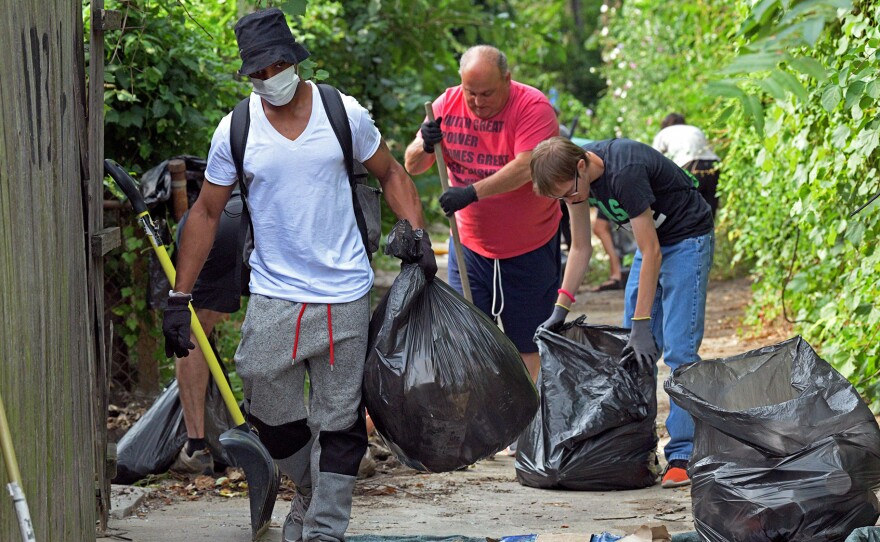 Volunteers clear an alley strewn with trash near Fulton Avenue in Baltimore on Aug. 5. Another group was in the city Thursday doing similar cleanup.