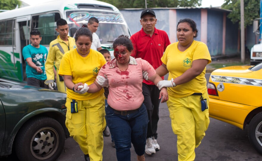 A wounded woman arrives at the offices of Comando de Salvamento. Her companions claim she was pushed from a bus by gang members.