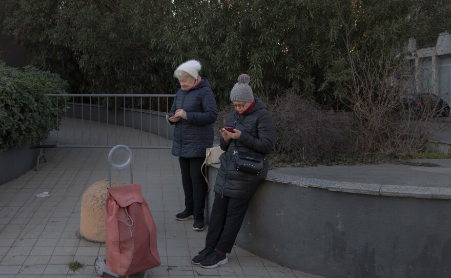 Liliya Khodunay stands with her friend Vira Zhmurko while they chat with family in their free time in Milan, Italy, in February 2023. Liliya and Vira are from the same city in Ukraine, which has been under attack since the first days of the invasion. They have been friends for a long time and have lived together since Russia invaded Ukraine, as Vira was visiting Italy and could not return home.