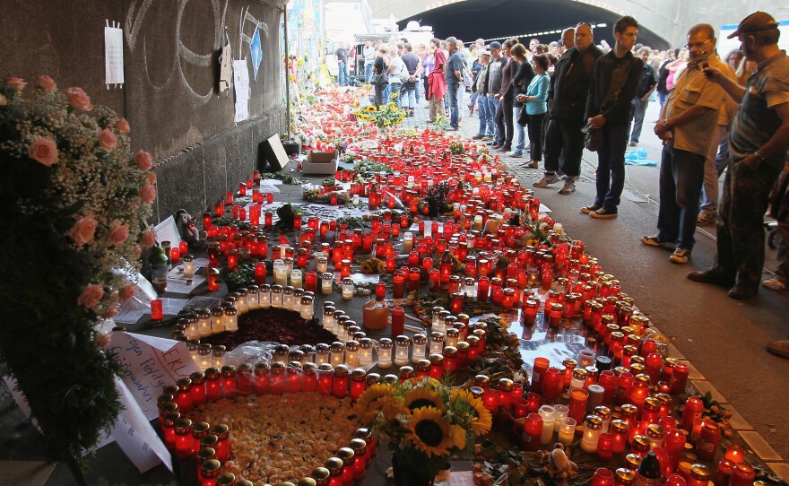 People mourn at the site of the Love Parade stampede on July 27, 2010 in Duisburg, Germany.