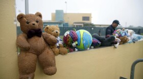 In this Saturday, June 23, 2018, file photo, a guard walks by toys placed for migrant children by protesters as they march to Homestead Temporary Shelter for Unaccompanied Children, in Homestead, Fla. 