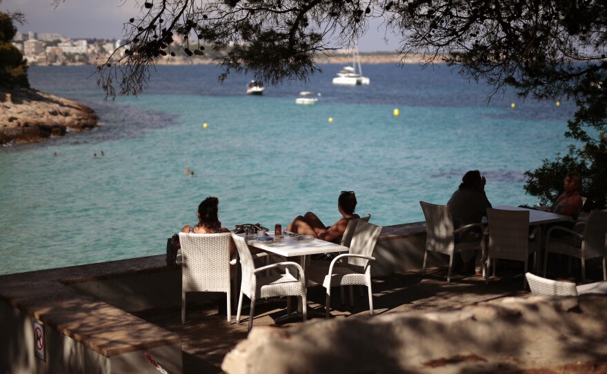 People sit in a terrace bar at the beach in Spain earlier this month, when many internal travel restrictions were lifted. The EU has decided on its first list of approved travel partners, as part of its reopening of external borders.