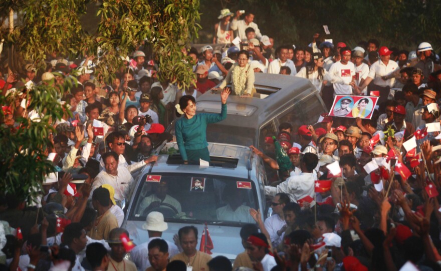 Supporters greet Myanmar's pro-democracy icon Aung San Suu Kyi, atop her vehicle, as she arrives at an election campaign rally in Thongwa village, Myanmar, on Sunday. The country's new government is holding legislative elections on April 1.