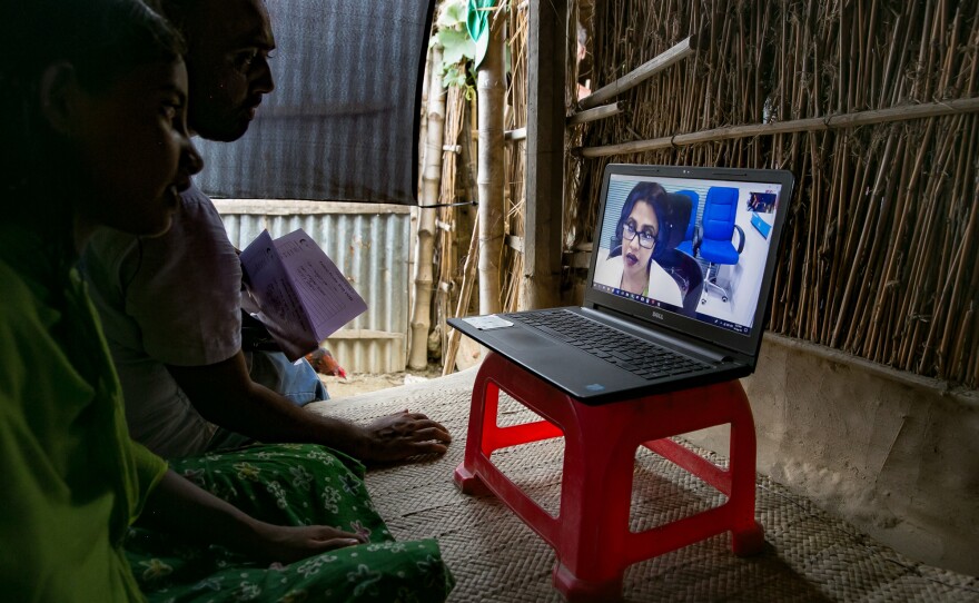 People speak to Dr. Tina Mustahid during a Teledaktar session on a char near Rajshahi, Bangladesh. For many patients, Dr. Mustahid is the first big-city doctor they've ever consulted. Instead, one-third of rural households visit unqualified village doctors<a href="https://www.ncbi.nlm.nih.gov/pmc/articles/PMC4821870/">,</a> called kabirajs, who rely on unscientific methods of treatment.