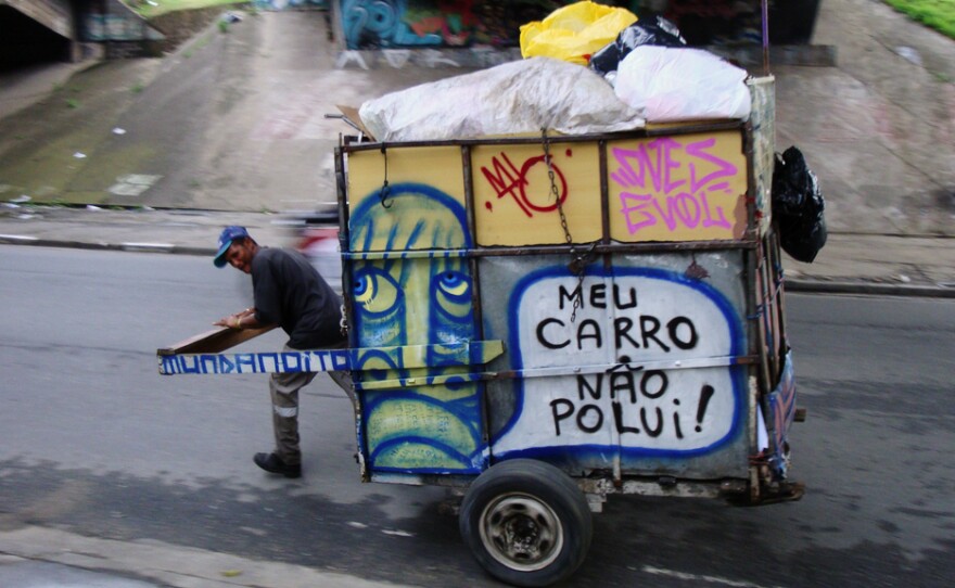 A waste picker wheels a trash cart with Mundano's art and spreads the word: "My cart doesn't pollute."