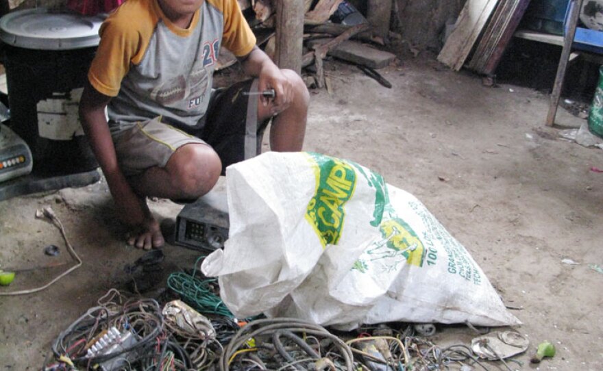 A boy who lives in Ocotillo, the village adjacent to the San Pedro Sula dump, strips insulation off electrical wires. His father, Santos Dauri Pineda, will sell the copper for scrap. Dauri normally paints cars for a living, but there has been no work lately; now, he is scavenging at the dump as well.
