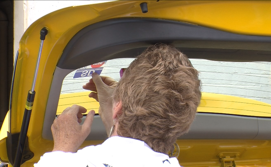 San Diego Councilwoman Marti Emerald applies a taxi permit decal to Adane Anjulo's cab on July 14, 2015.