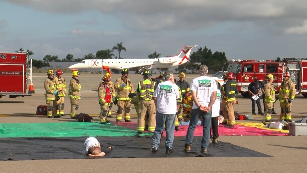 A JSX plane on the runway in the background as emergency crews conduct a disaster drill at McClellan-Palomar Airport, Oct. 23, 2025.