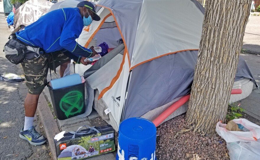 David Scott loads supplies into his tent home in downtown Denver. "As long as they keep it to where we're getting cleaned, not swept, it's all right," says Scott.