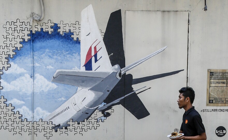 A waiter walks past a mural of Flight MH370 in Shah Alam outside Kuala Lumpur, Malaysia, in February 2016. The flight disappeared nearly three years ago with 239 people on board, and the search for the plane has now been suspended.