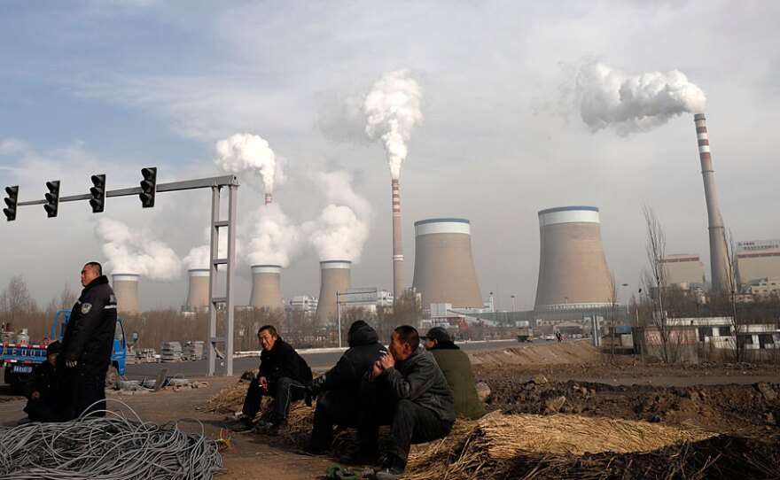 Workers rest in front of the cooling towers of a coal-fired power plant in Dadong, China. Such plants are a major contributor to carbon dioxide emissions.
