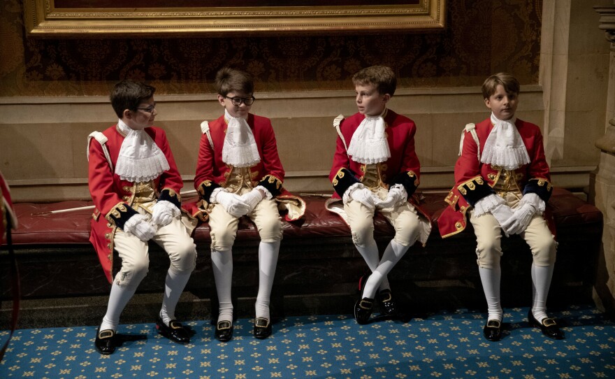 Page boys sit together before lining up for the arrival of Queen Elizabeth II at the Palace of Westminster for the State Opening of Parliament on Oct. 14, 2019.