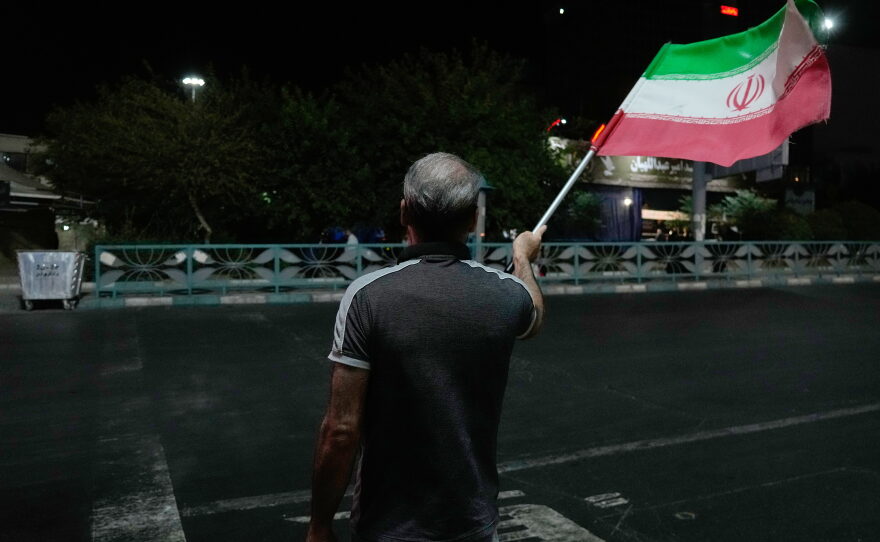 A pro-government demonstrator waves an Iranian flag in a gathering commemorating the late Iranian Supreme Leader Ayatollah Ali Khamenei at a square in Tehran, Iran, Saturday, July 11, 2026.