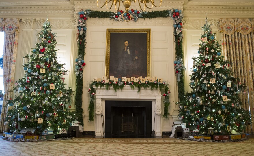 Christmas trees flank the fireplace in the East Room of the White House. Every year, about 100 volunteers decorate the White House with garlands, ribbons and lights.