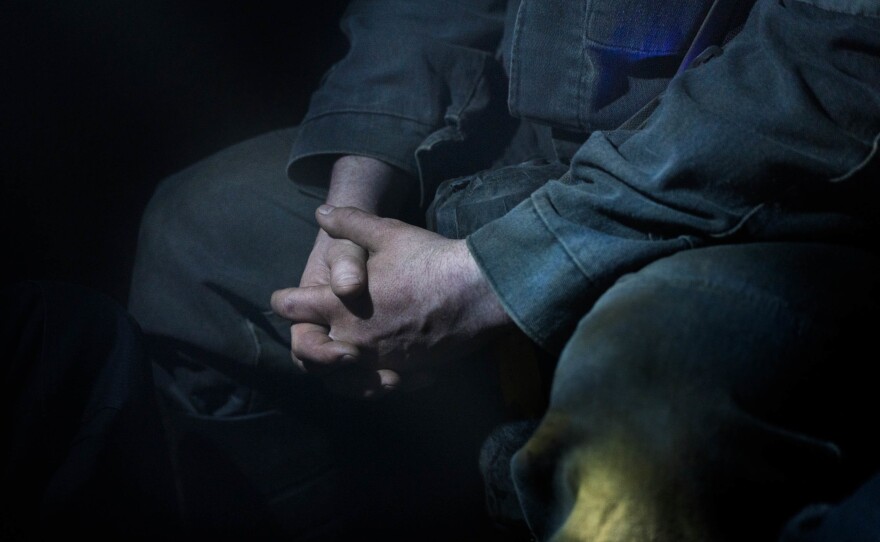 A mine employee folds his hands as he sits in the mine railway awaiting his stop. For miners in eastern Ukraine, who have long watched their industry erode, the shift in rhetoric and renewed focus on coal is being seen as an opportunity.