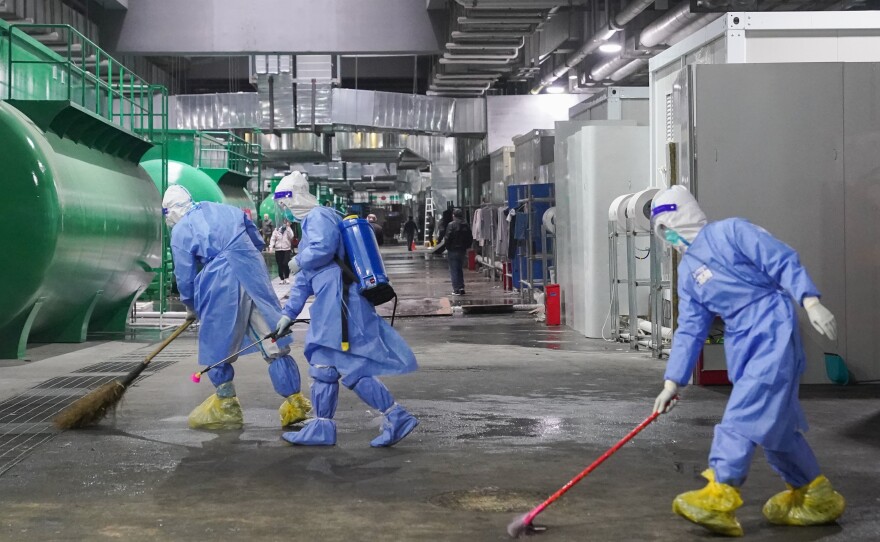 Workers clean and disinfect the floor at the National Exhibition and Convention Center NECC, the largest makeshift hospital, in Shanghai. Many jobs in these temporary facilities are drawn from the pool of unemployed migrant workers.