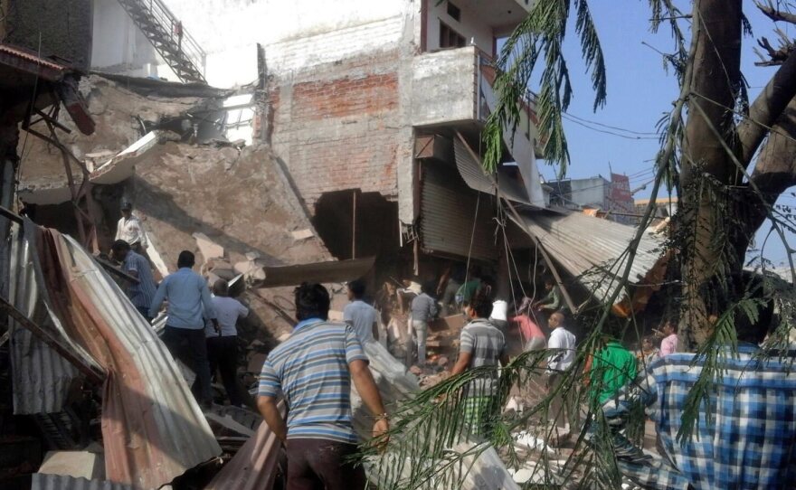 People gather at the site of an explosion in Jhabua, Madhya Pradesh, India, on Saturday. Scores of people were killed in twin blasts linked to cooking gas cylinders.