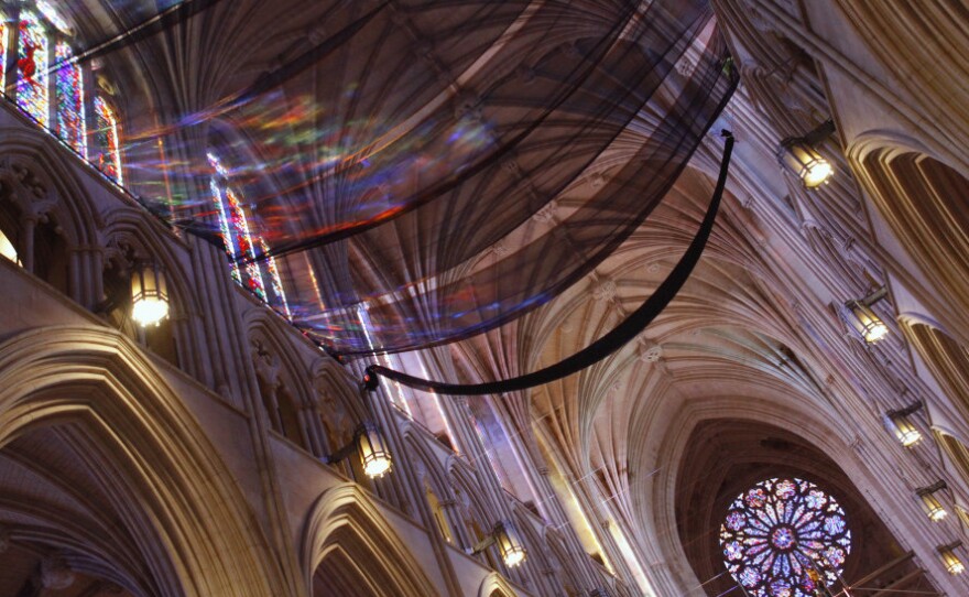 Light from stained glass windows shines onto safety nets that have been installed along the ceiling of the nave at the National Cathedral, as a precautionary measure after parts of the structure was damaged in an earthquake.