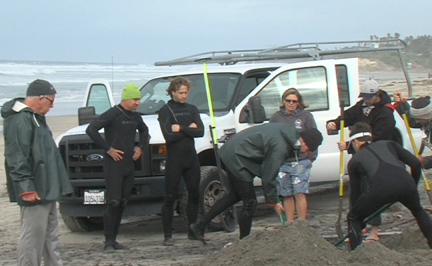 A team from the Scripps Institution of Oceanography buries one of a number of sensors along the beach in Cardiff to test the wave heights and water currents, Jan. 6, 2016.