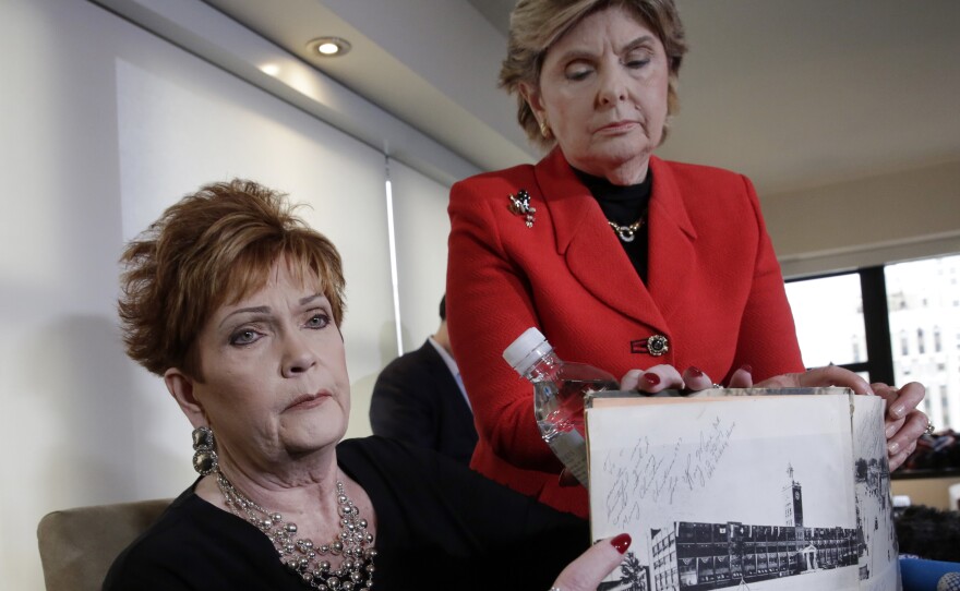 Beverly Young Nelson (left), who has accused Alabama Republican Roy Moore of sexual misconduct, and her attorney Gloria Allred hold Nelson's high school yearbook that Nelson says was signed by Moore. Nelson now says she added notes to the inscription.