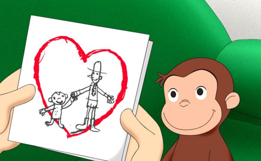 The Man with the Yellow Hat holds a Valentine's Day card from Curious George.