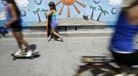 Skateboarders, body boarders and bikers pass along the Mission Beach boardwalk in San Diego, June 24, 2014.