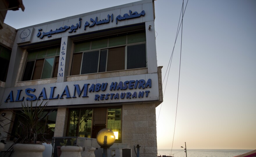 The sun sets over Al Salam Abu Haseira fish restaurant by the beach.