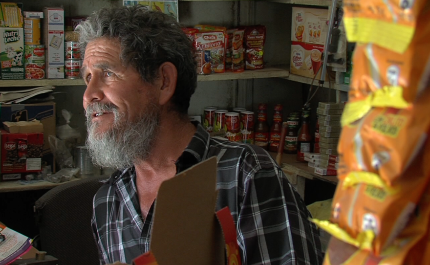 Jacumé resident José Mercado stands behind the counter of a supermarket near the center of town, Sept. 27, 2015.