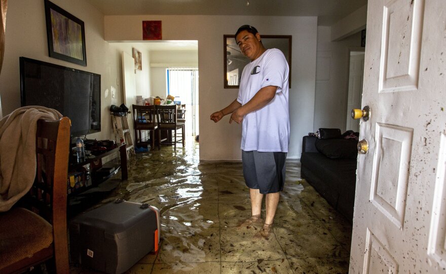 Olban Tremeneo Lagos, 42, points to the water inside his apartment in the Little Havana neighborhood of Miami, on Saturday.