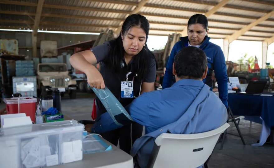 UCSF-Fresno Medical student Darlene Tran checks the blood pressure of a farmworker in an equipment barn during part of the Rural Mobile Health program visit at a farm outside of Helm on June 16, 2025.