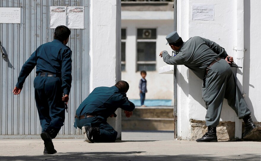 Afghan police gesture to four-year-old Ali Ahmad on Aug. 25 after a suicide attack on a Shiite mosque in Kabul.