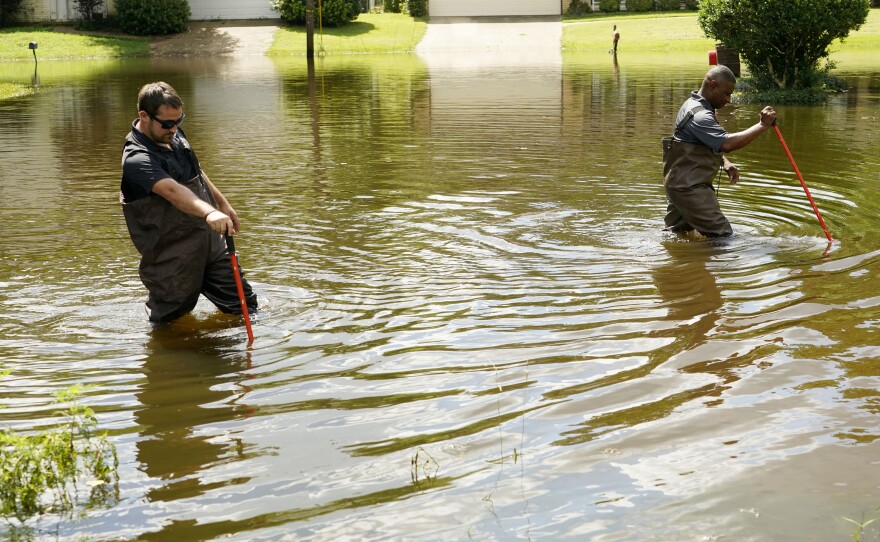 Hinds County Emergency Management Operations Deputy Director Tracy Funches (right) and Operations Coordinator Luke Chennault wade through floodwaters in Jackson, Miss., on Monday.