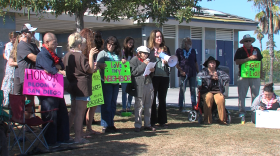 Attorney Ann Menasche is shown speaking into a bullhorn, surrounded by RV owners at South Shore Boat Launch on November 4, 2025.