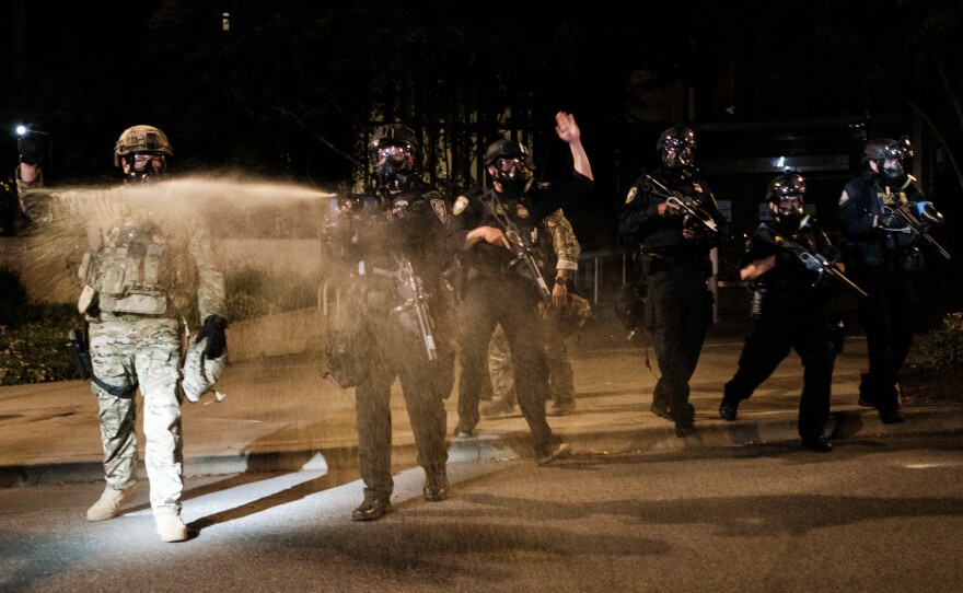 Federal officers use tear gas and other crowd dispersal munitions on protesters Friday outside the Multnomah County Justice Center in Portland, Ore.