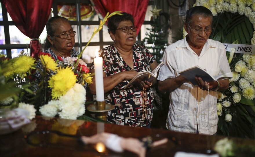 People pray next to the coffin of slain journalist Gumaro Perez Aguilando during his wake at his mother's home in Acayucan, Veracruz state, Mexico, on Dec. 20.