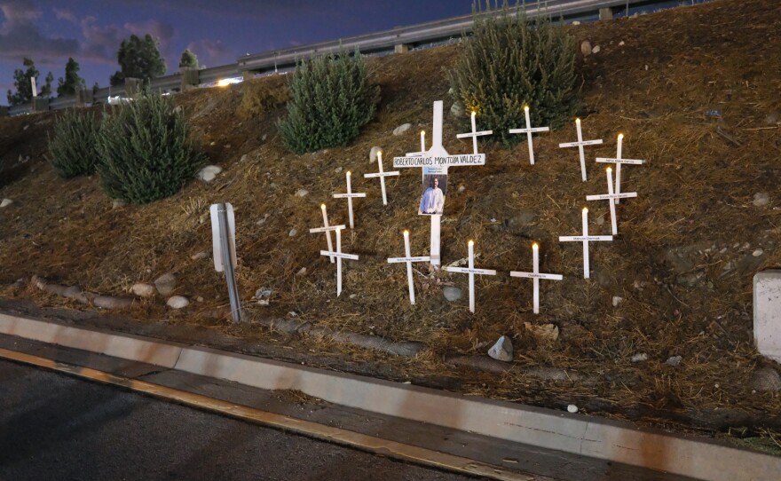 A memorial for Carlos Roberto Montoya Valdez (his first and second names are erroneously transposed on the cross). Activists said Montoya was killed while running across the freeway to escape an ICE raid of day laborers at the Home Depot parking lot across the street.  Los Jornaleros — many of the band's members are day laborers themselves — played at a memorial vigil for him.